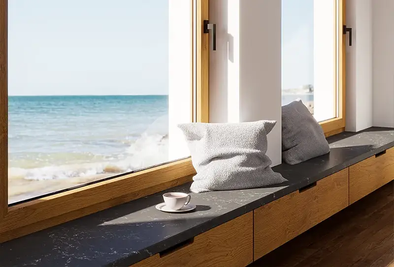 Dunkle Fensterbank aus Quarzkomposit an gro&szlig;em Fenster mit Meerblick &ndash; moderne und langlebige L&ouml;sung f&uuml;r K&uuml;che und Wohnr&auml;ume